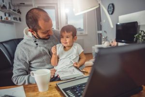 Vater wird von Baby beim Arbeiten im Virtual Office abgelenkt
