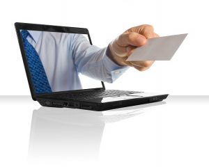 Hand reicht Visitenkarte als Symbol für Online-Präsenz aus dem PC